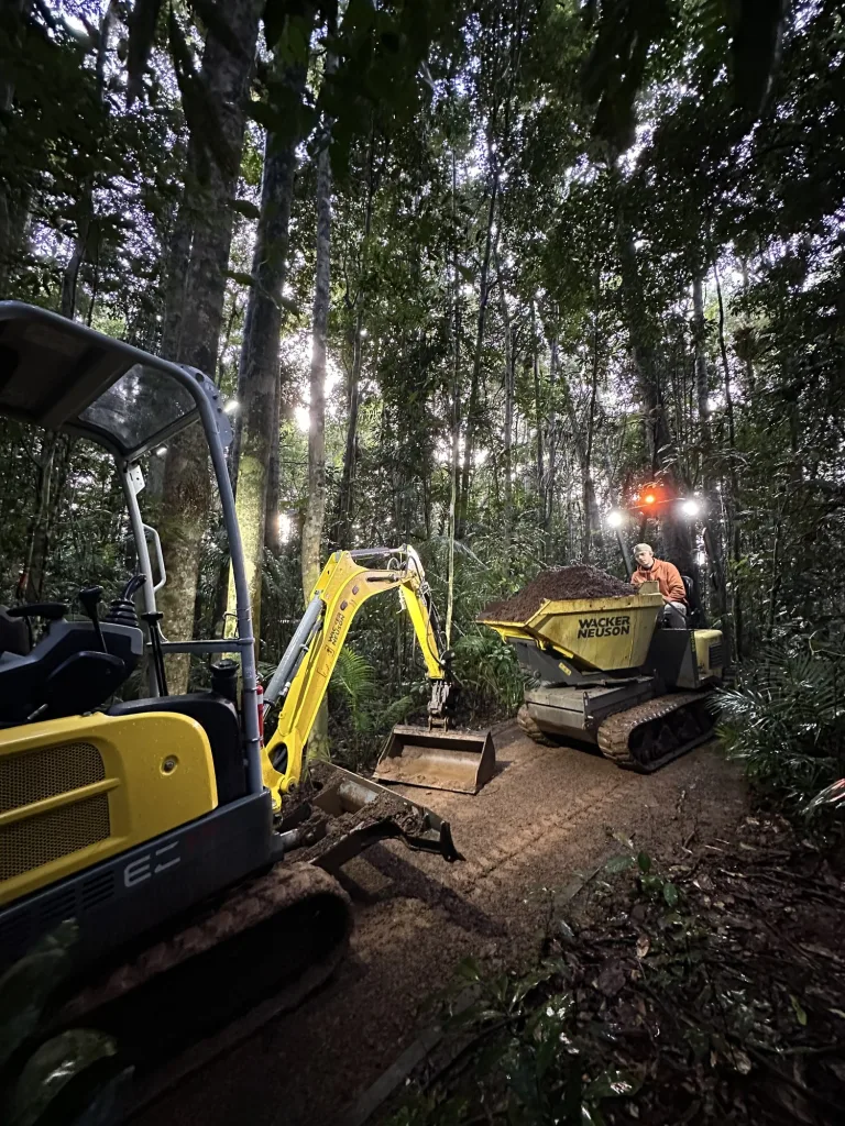 Two excavators building trail through dry open forest